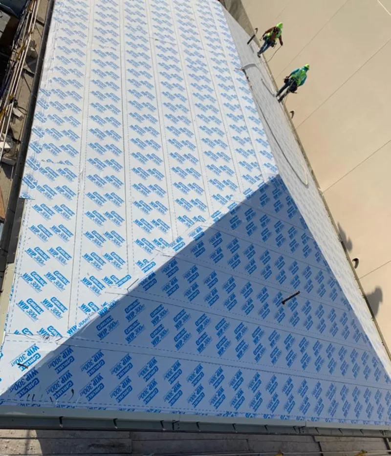 Professional roofers installing underlayment on a metal roof in Somersworth